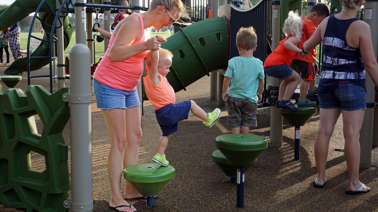 Kid and mother climbing on playground at Conrad Fischer Park, Elmhurst, Illinois