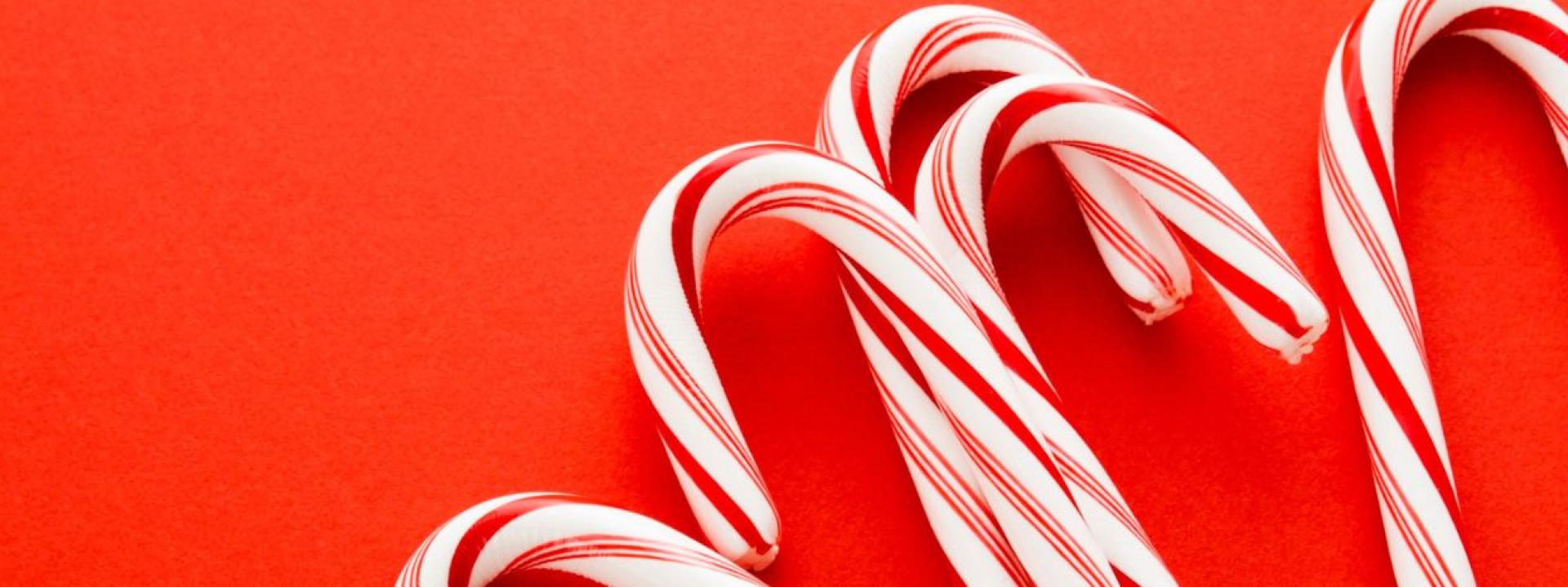 Close-up of red-and-white striped peppermint candy canes on a red background.