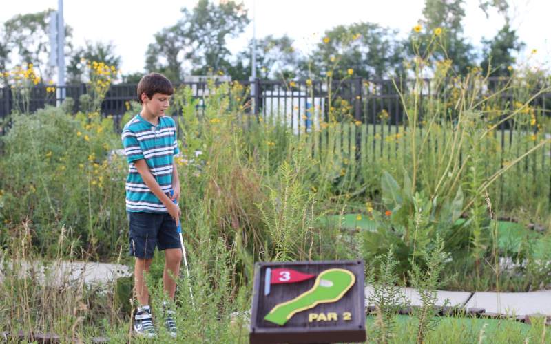 Teen playing mini golf 