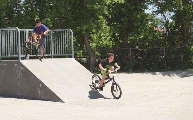 two kids going down a ramp at a skate park