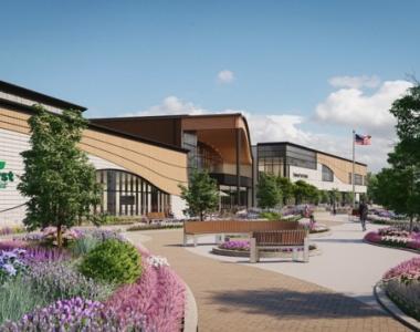 Rendering of a modern park district building with the “Elmhurst Park District” logo on a curved facade, landscaped beds of grasses and flowers, and people walking along a path.
