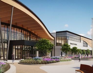 Rendering of a modern building with curved wooden overhang and glass windows, landscaped shrubs and grass.