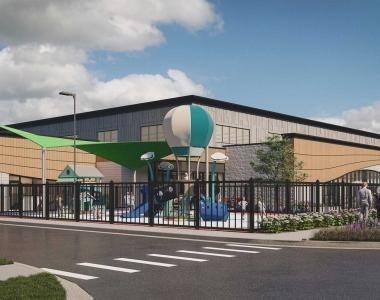 Rendering of a building with large windows and a playground in the foreground featuring shade structures and play equipment.