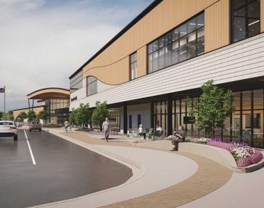 Rendering of a building with large windows, landscaping borders with grasses and a parking lot on the left.