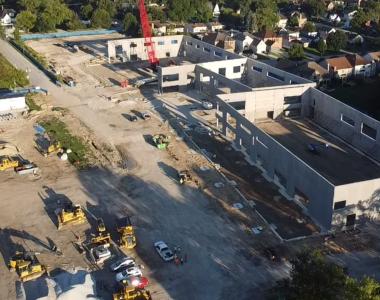 Aerial view of Wagner Community Center construction site with earthworks, construction vehicles and trucks, and partially built concrete buildings