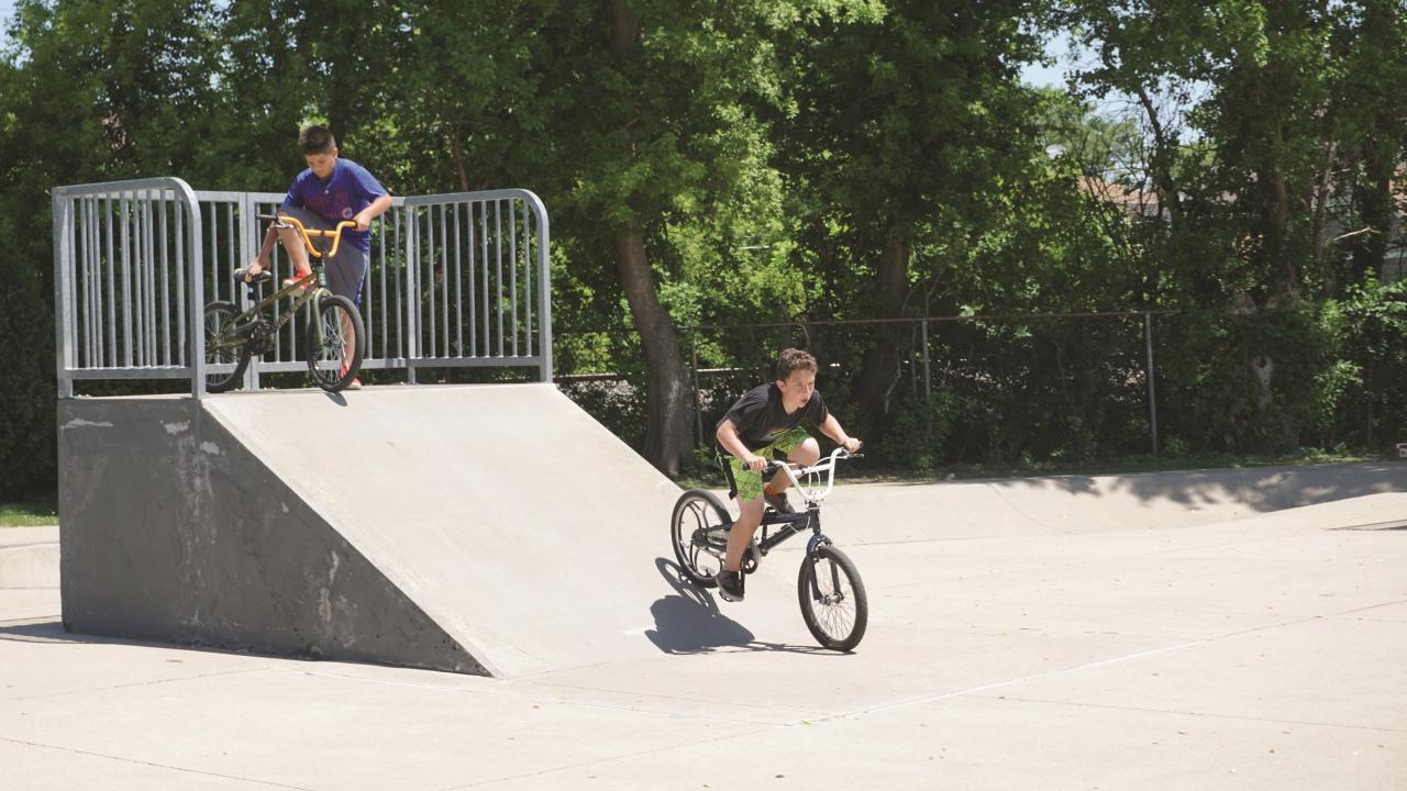 two kids going down a ramp at a skate park
