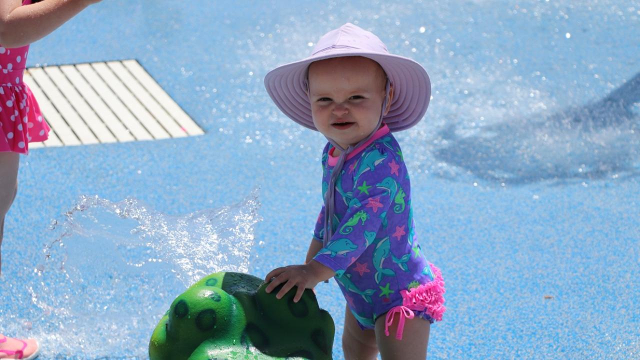 Toddler at a spray ground with a frog statue
