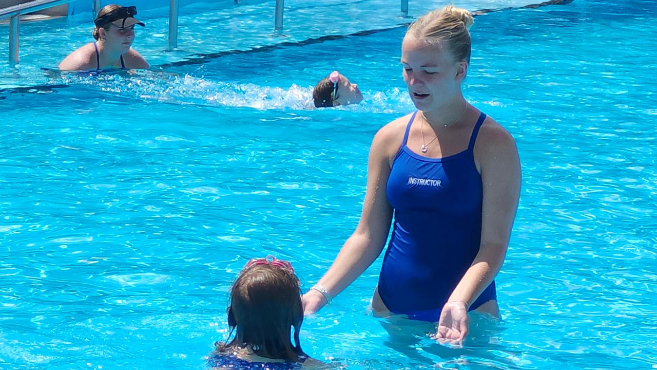 A swim instructor assisting a child in lessons