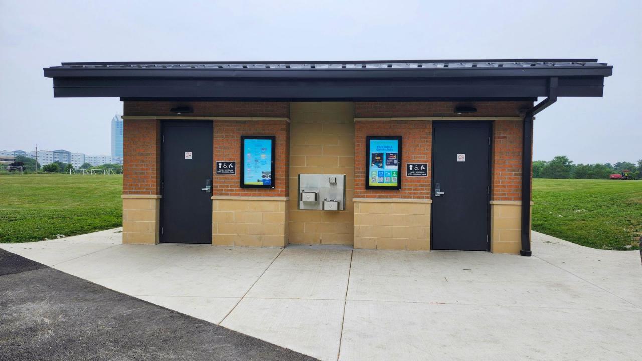 Eldridge Park year-round restroom building was completed in March 2026. A brick restroom building with two dark doors, a water fountain, set against a grassy field and sky.