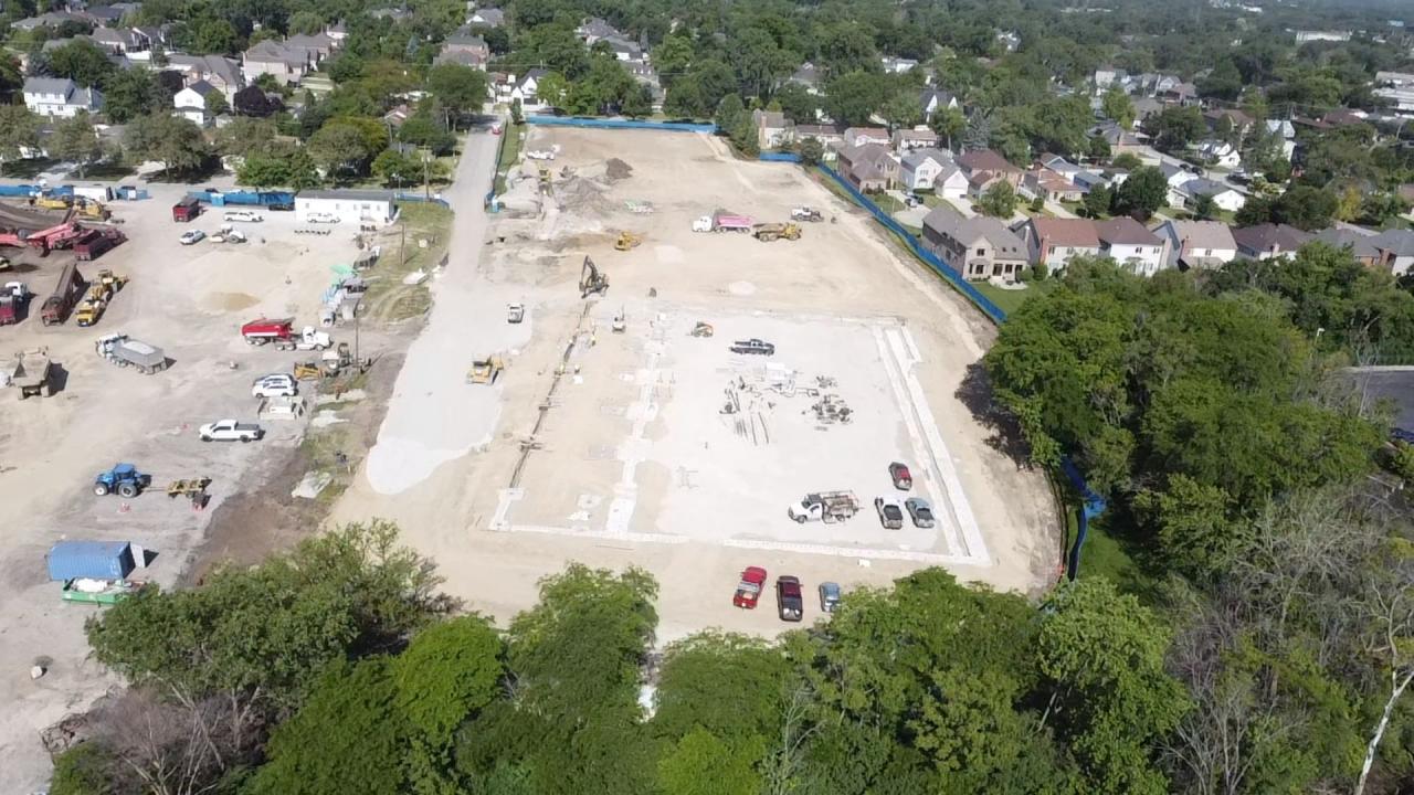 An aerial view of the Wagner construction site, Summer 2026. An aerial view of the Wagner construction site with various heavy machinery, trucks, and vehicles scattered across the cleared land.