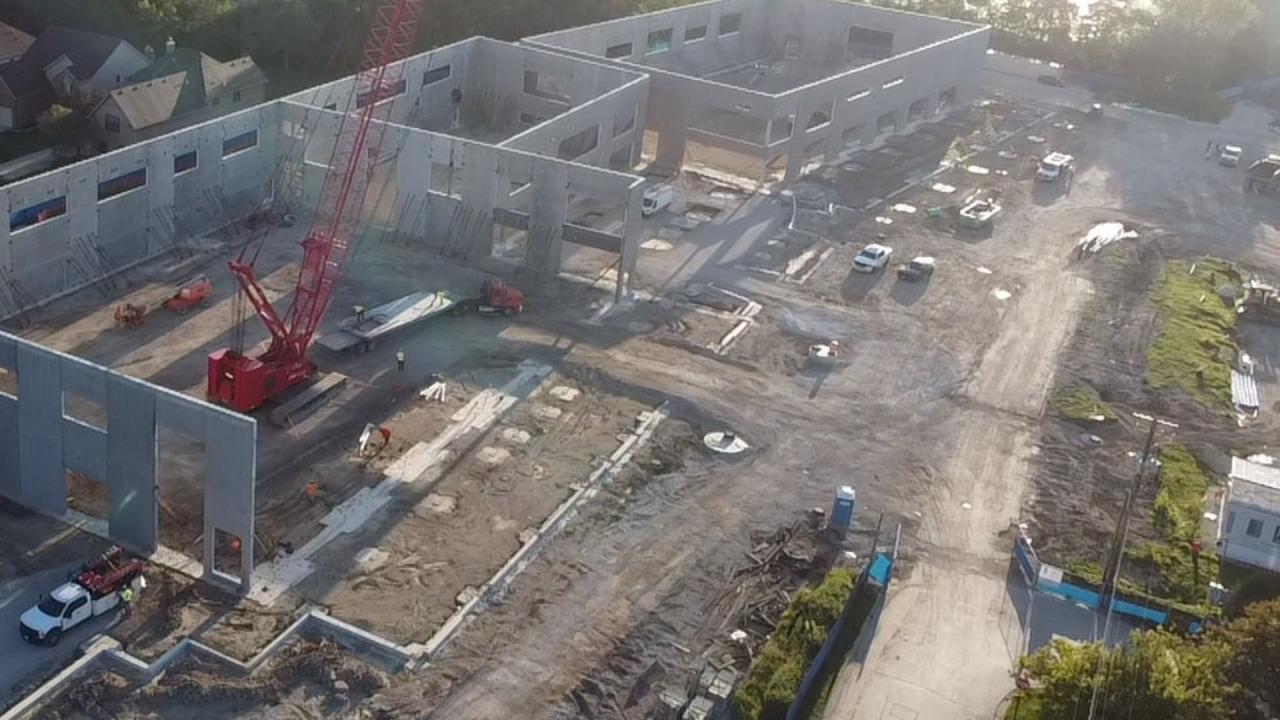 Aerial view of a construction site with a partially built building, cranes and vehicles.