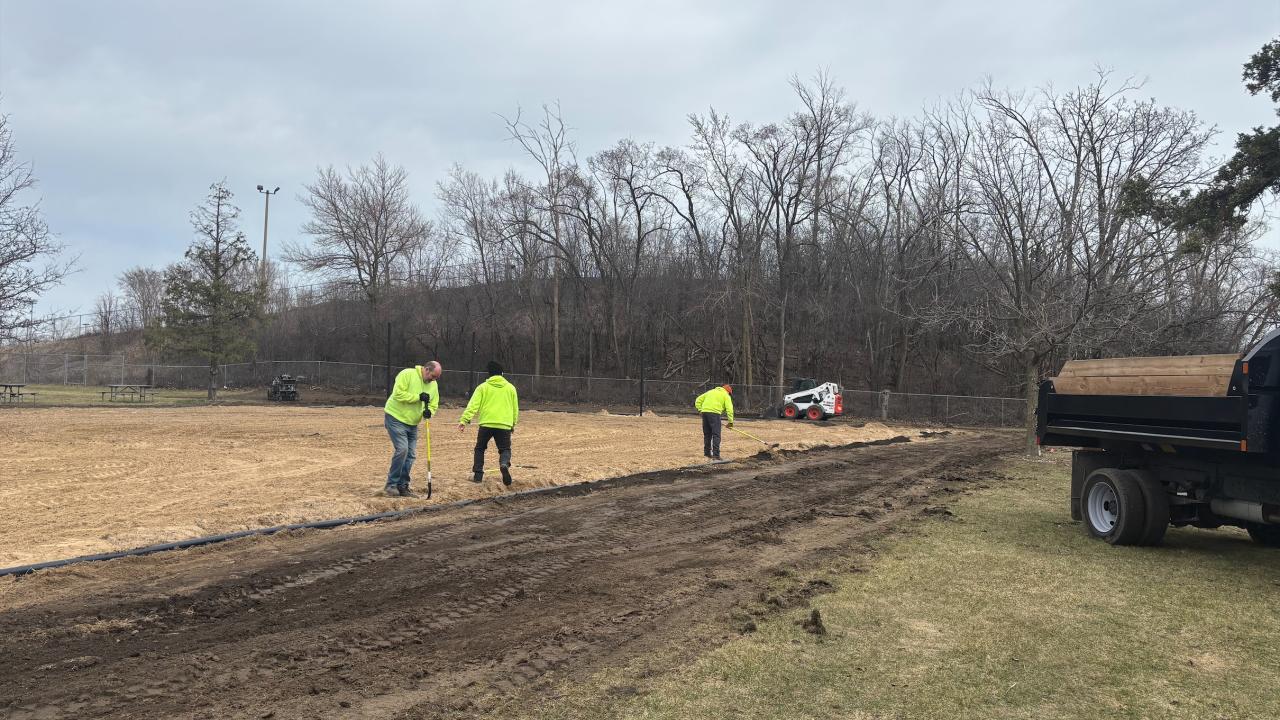 Staff installing a permanent edge to the sand courts